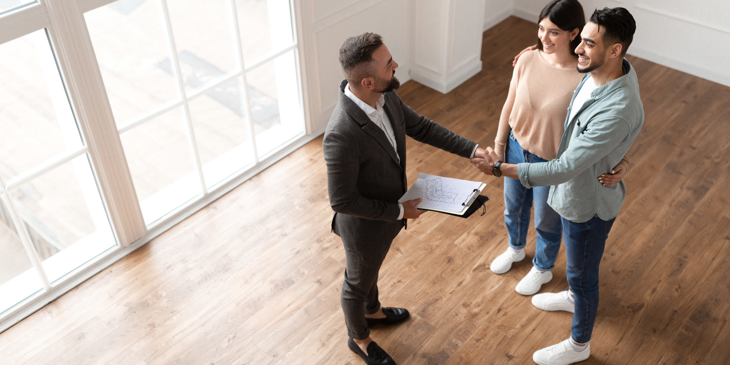 Couple Buying New Apartment, Shaking Hands With Realtor